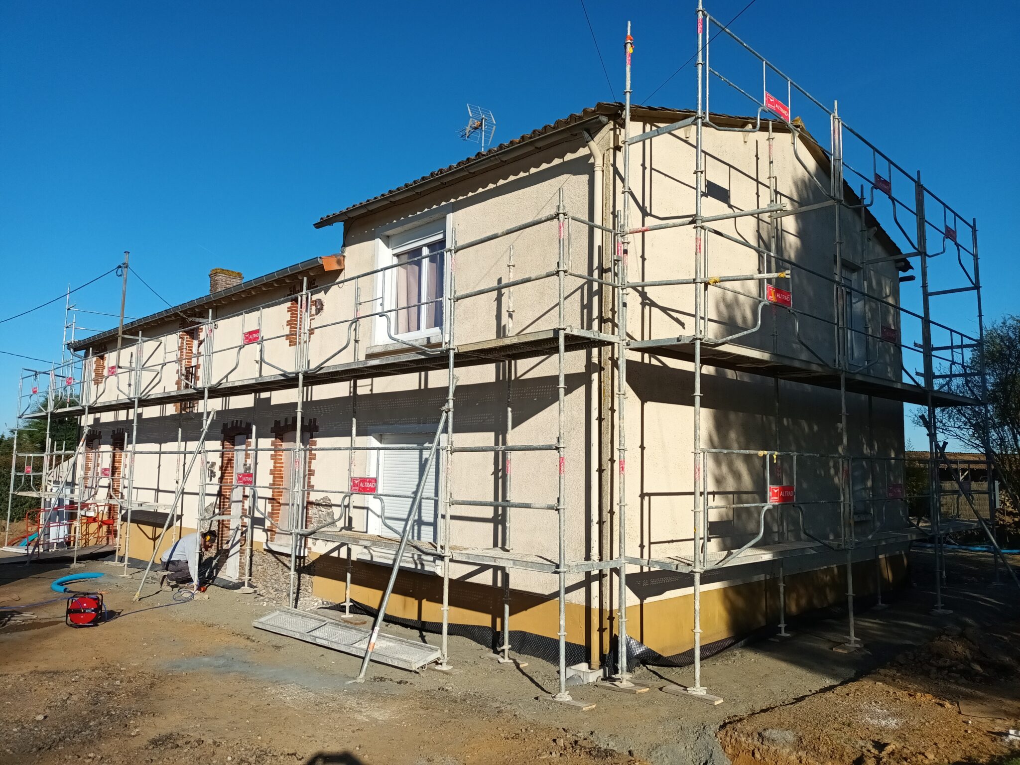 Façade de maison mêlant pierre ancienne et extension moderne, en cours de rénovation multilatérale pour harmoniser les matériaux et remettre le bâtiment en valeur.