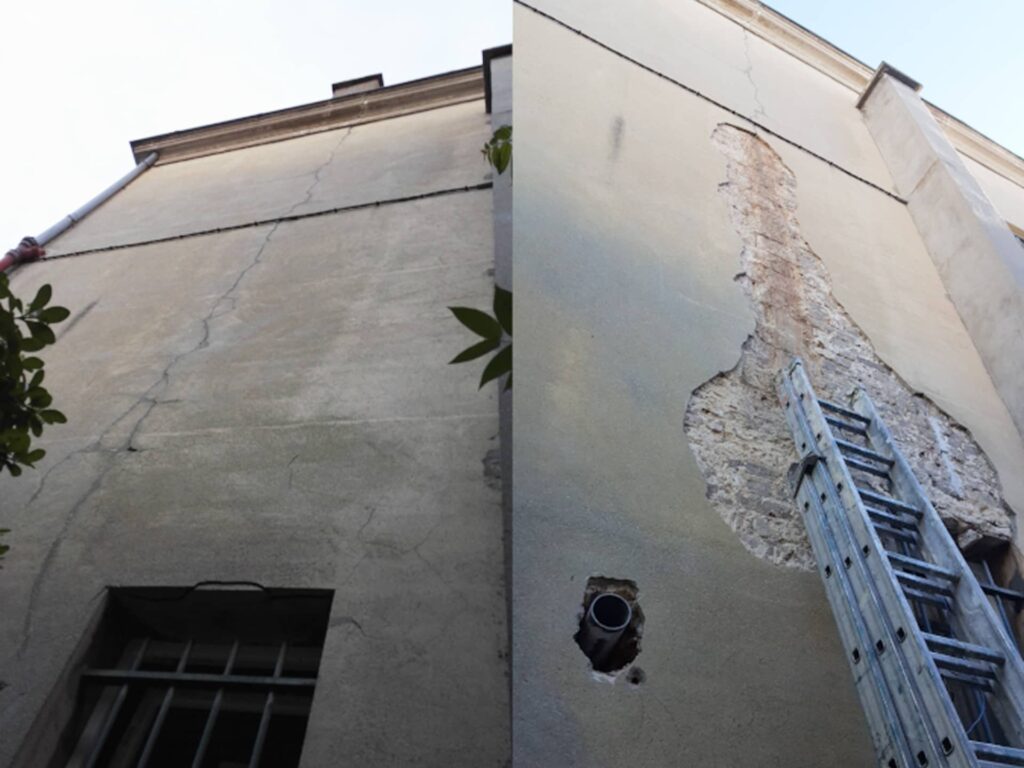 Zone d’enduit qui se décolle en plaques sur une façade, révélant un support détérioré nécessitant une reprise complète.